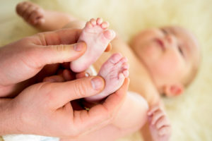 father or doctor massaging small baby's foot